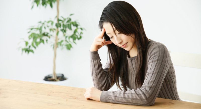 頭痛で頭を抱えている女性