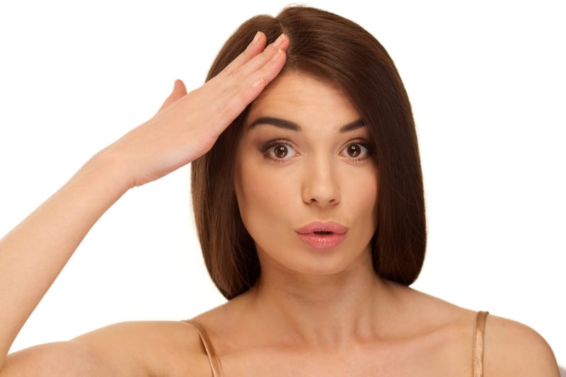 額に手を触れる女性
