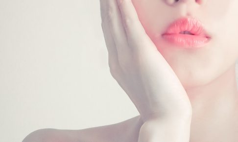 頬に手を当てる色白の女性