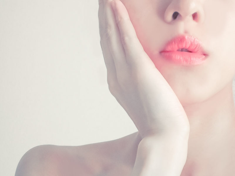 頬に手を当てる色白の女性