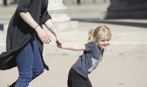 大人の手を引っ張る金髪の子供