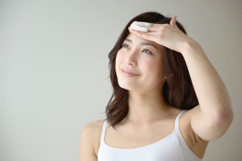 コットンをおでこに当てる女性