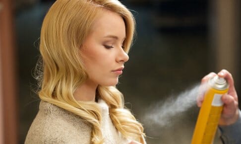 ヘアスプレーを塗る女性