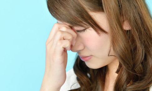 目を押さえる女性の画像