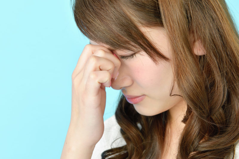 目を押さえる女性の画像