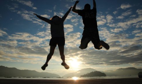 朝日に向かってジャンプをしている人