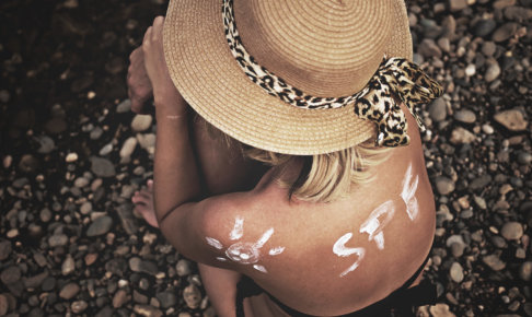 日焼け止めで背中に文字を書く帽子を被った外国人女性