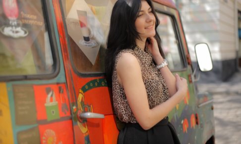 ごちゃごちゃした色の車によりかかる外国人女性