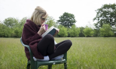 公園で椅子の上で読書する女性