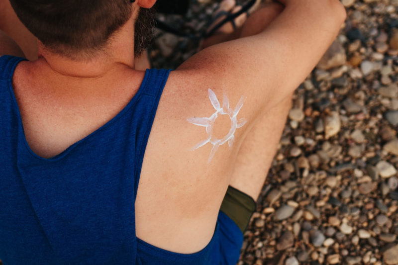 腕に日焼け止めを使って太陽の絵を描いた男性