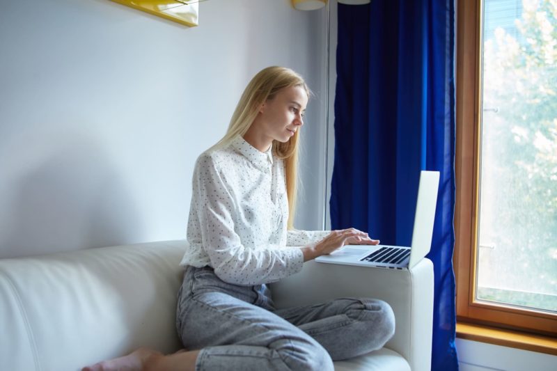 ソファーに座ってパソコンを入力している外国人女性