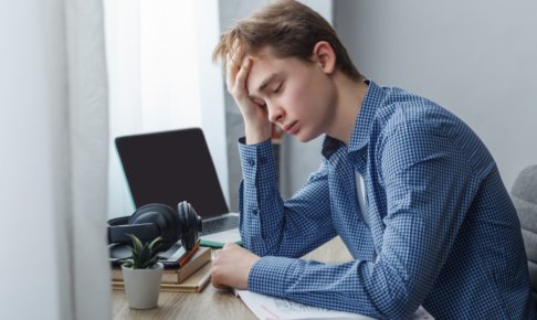 窓際で悩む男性