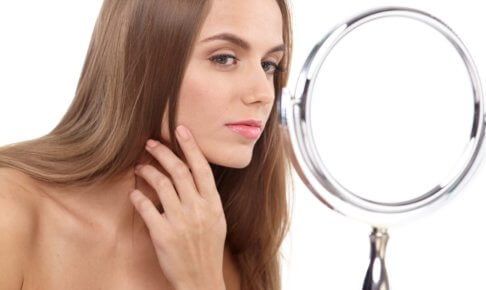 鏡で入念に肌の状態を確かめている女性