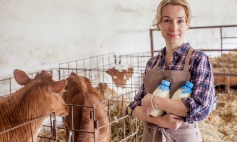 牛舎で牛乳瓶を抱えている外国人女性