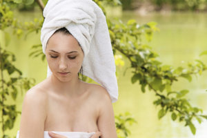 森と湖の中で体にタオルを巻いている女性