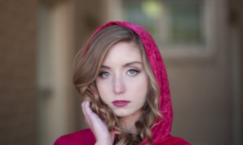 髪の毛に手を触れている赤ずきんの外国人女性