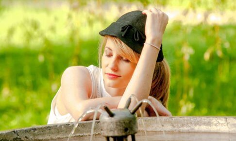 噴水で帽子に手をあてている外国人女性