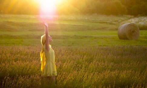 ラベンダー畑で日の光を浴びている黄色い女性