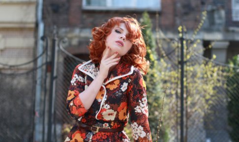 アゴに手を当てている花柄の服の外国人女性