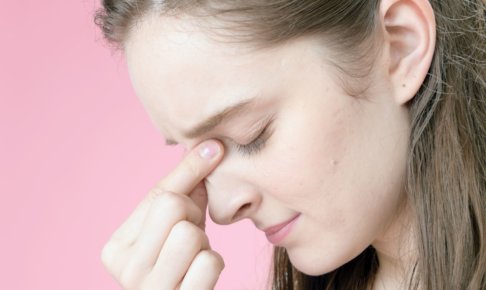 痛そうに眼を抑えている女性