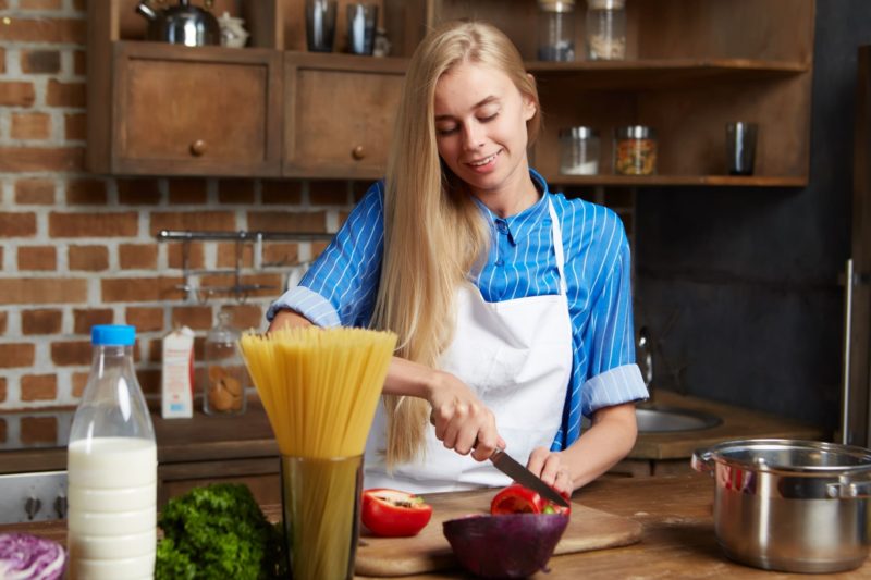 パプリカを切っているキッチンの女性