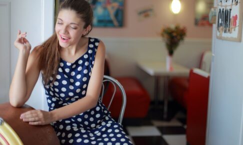 椅子に座っている水玉模様のワンピースを着用している外国人女性