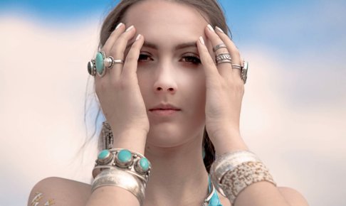 額に両手を当てているエメラルドグリーンの指輪をはめている外国人女性