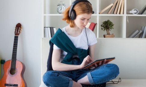 ベットの上でタブレットを操作している外国人女性