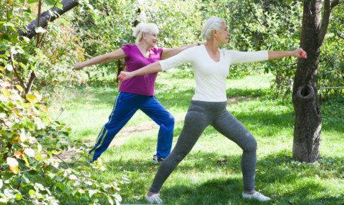 森林でヨガをしているシニア女性2人