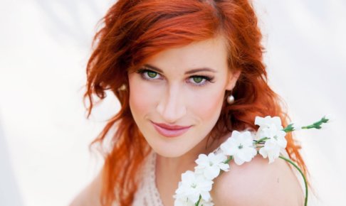 肩に白い花をかけたテラコッタ色の髪の女性