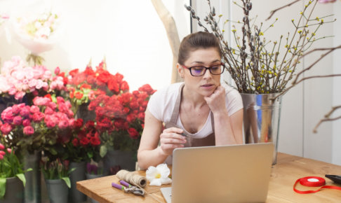 ノートパソコンで売り上げをチェックしている花屋店員