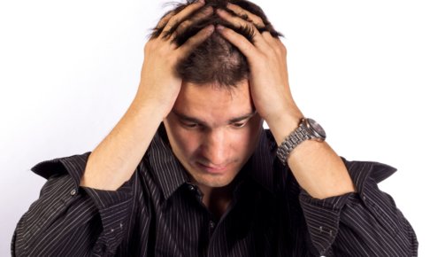 頭を抱えて落ち込んでいる外国人男性