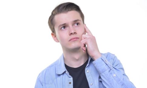 こめかみのあたりを気にするデニムジャケットの白人男性