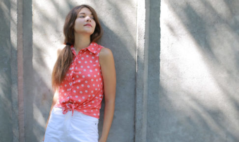 顔を上向き加減で立っているピンクの水玉を着ている女性