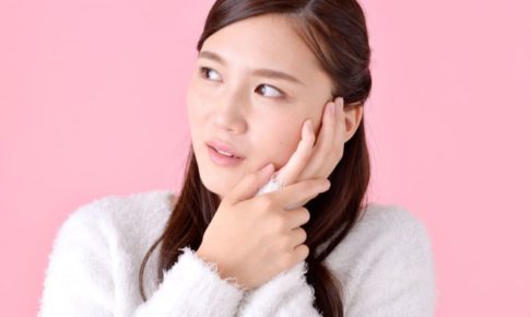 片方の頬を押さえながらチラッと右側を見ている女性