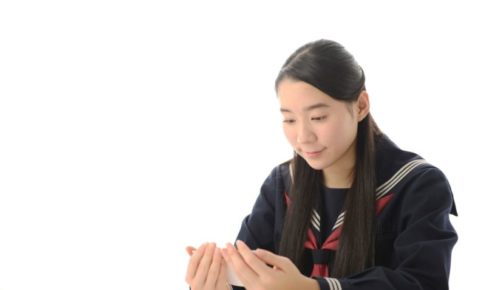 スマホを見ながら楽しそうに過ごしている女子中学生