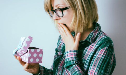 紫のボックスを開けて中身にびっくりしている女性