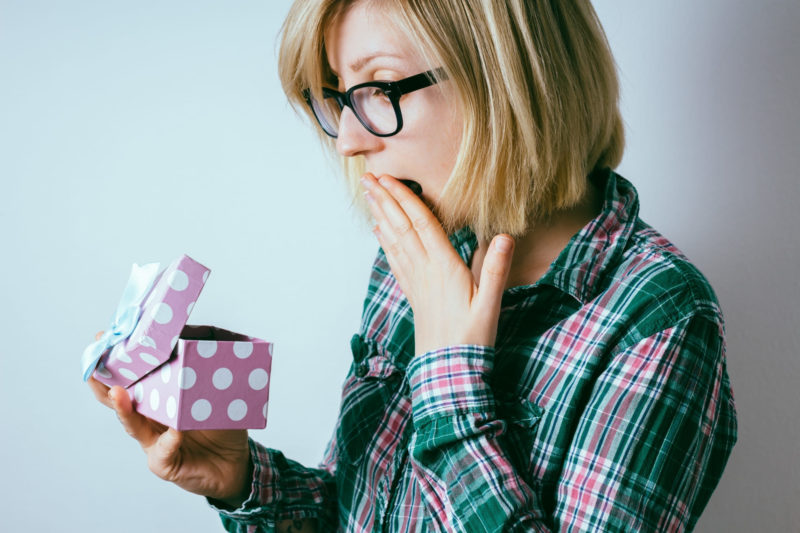 紫のボックスを開けて中身にびっくりしている女性
