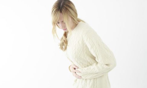 胃や腸の具合が悪く腹を押さえている女性