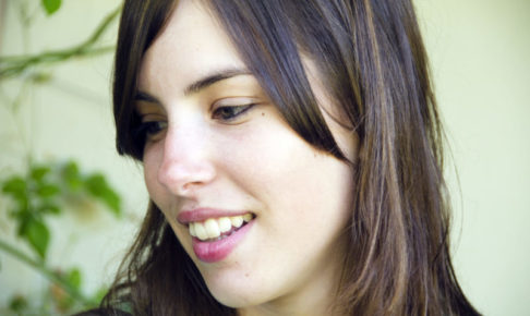 左側を向いて少し歯を出して笑っている外国人女性