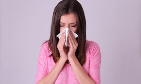 鼻をかんでいるピンクの服着た外国人女性