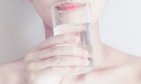 微笑みながら水を飲んでいる女性の顎のアップ