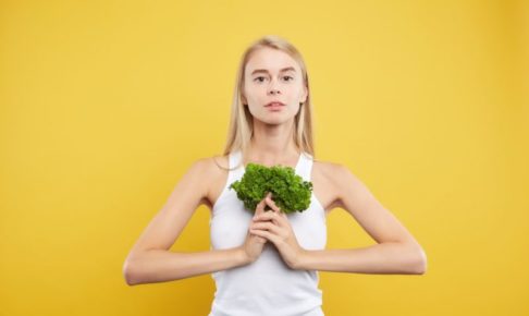 黄色い背景でパセリを持ってポーズを決めている女の子