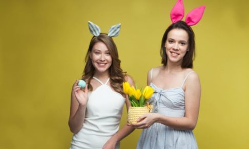 黄色い背景で卵と黄色いチューリップを持っている女性