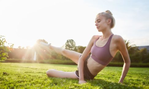 太陽に向かって足を上げてストレッチをしている女性