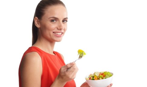 サラダを食べているオレンジのノースリニットを着ている女性