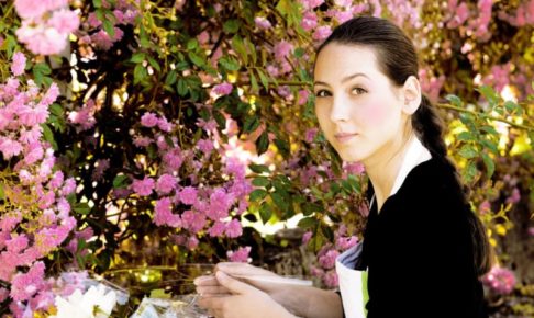 ピンクの花を手入れしている花屋の三つ編みした女性