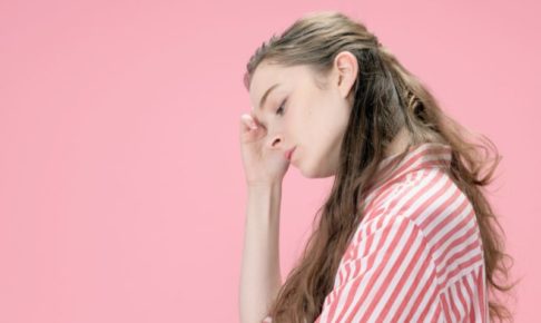 ピンクの背景で疲れていそうな眠そうな女性の横顔