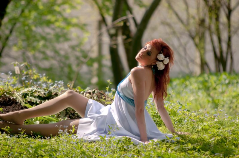 草原で座る赤毛の女性