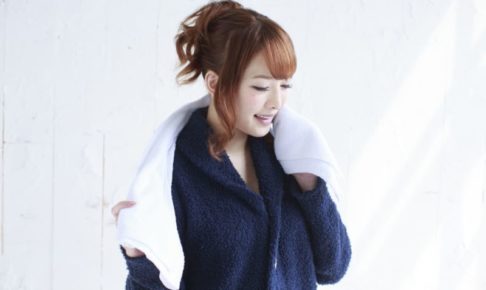 紺のパジャマを着て白いタオルを首にかけているお風呂上がりの女性